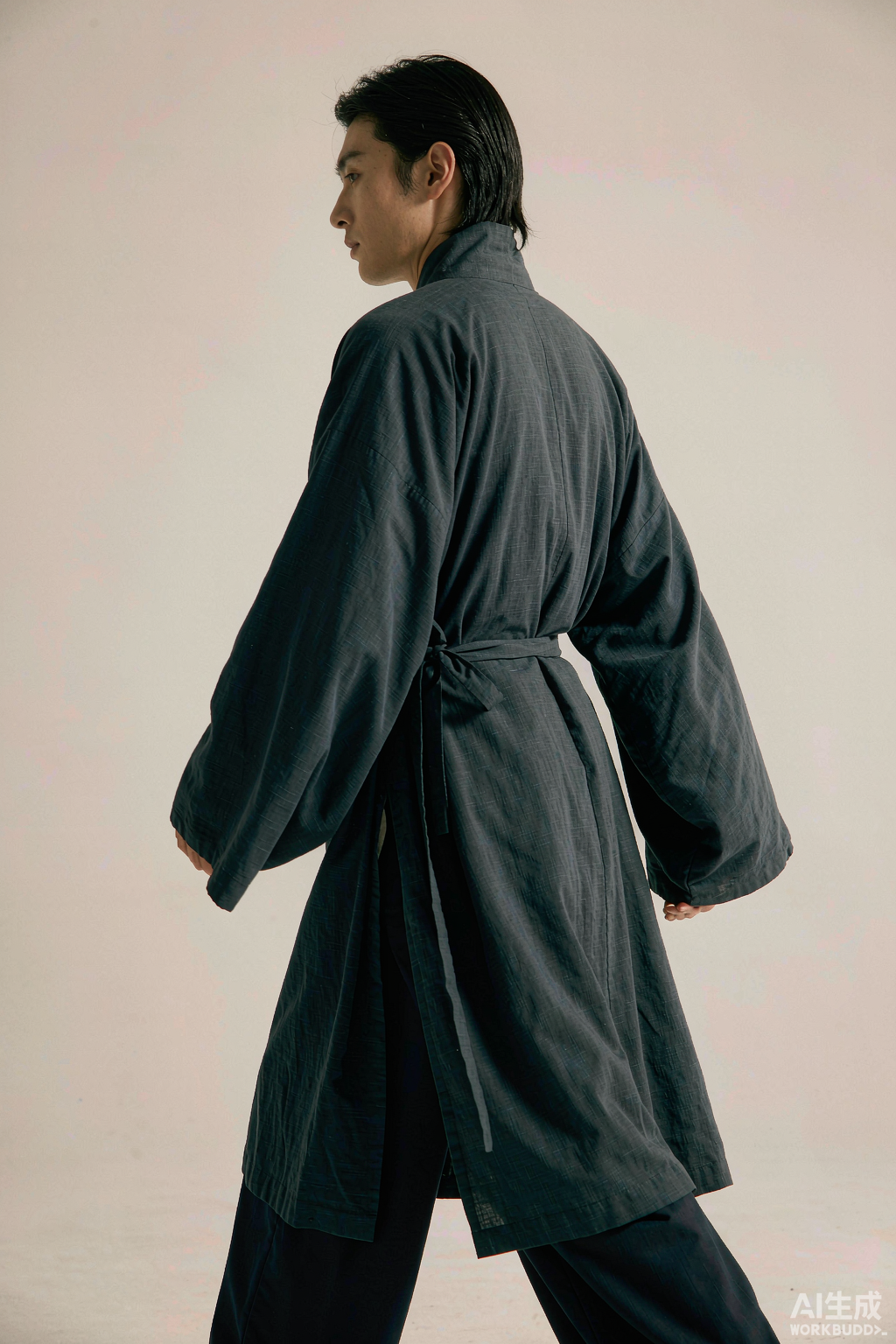 一位男士身着玄青色交领右衽宽袖长袍，背影侧身站立，宽袍大袖自然垂落、腰间束带，衣摆过膝